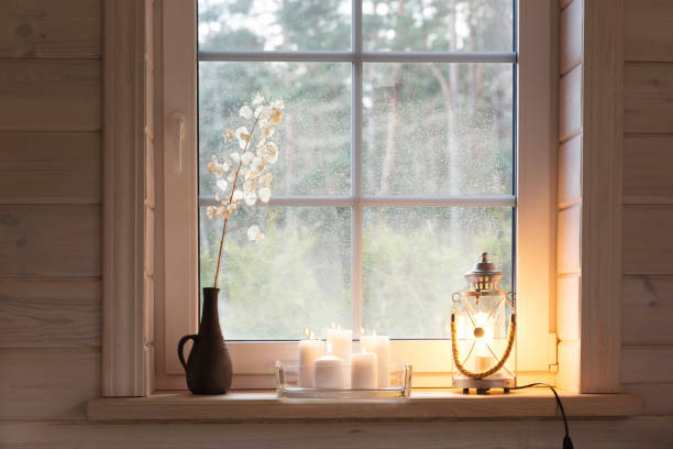 istock Beautiful burning candles and a lantern on the windowsill indoors 1811802410