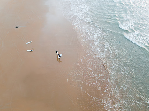 A beach with some surfers as seen from above