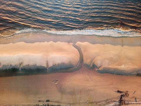 Aerial shot of a tranquil beach with blue water and golden sand