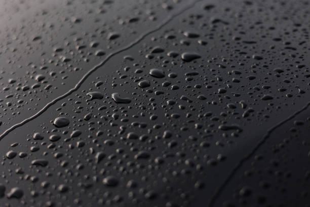 istock Rain or water drops different size on a black shiny car hood surface. Water droplets on dark iron surface and texture. Abstract background and water texture for design. 1811922313