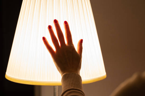 istock a woman's hand touches a floor lamp in a dark room 1811938850