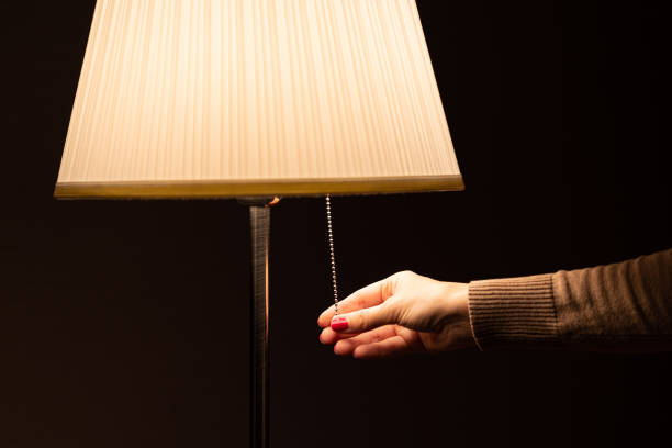 istock woman's hand turns on the floor lamp 1811952052