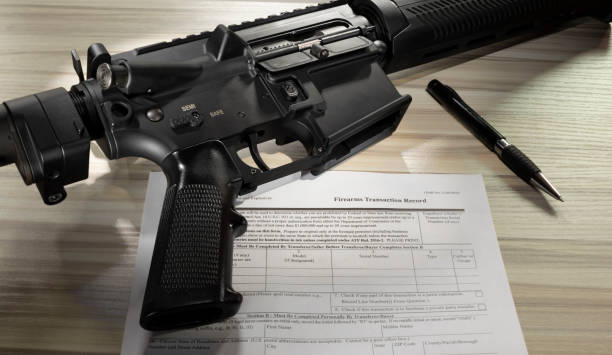 istock Assault rifle with pen and public domain background check form 1811963351