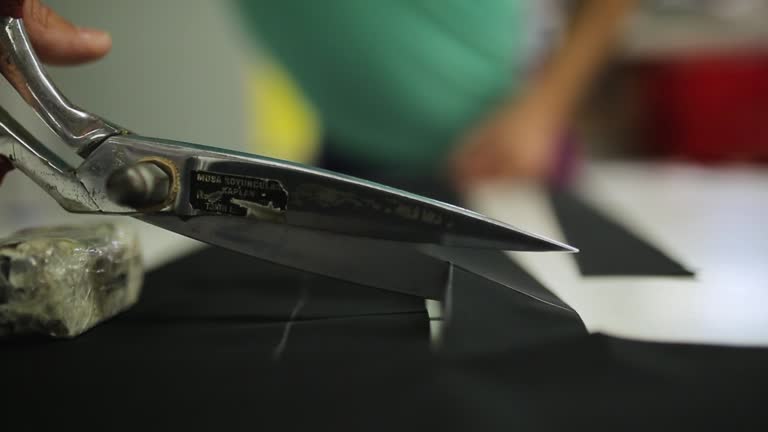 Hands Cutting suit fabric with scissors, Cutting a fabric with scissors on table in atelier