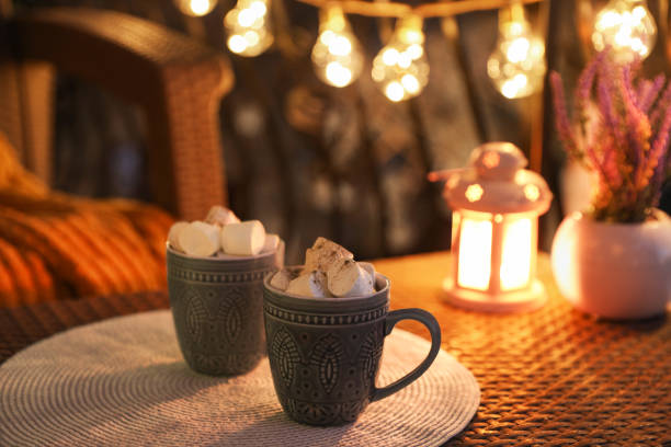 istock Cups with tasty cocoa and marshmallows on rattan table at balcony in evening 1812001321