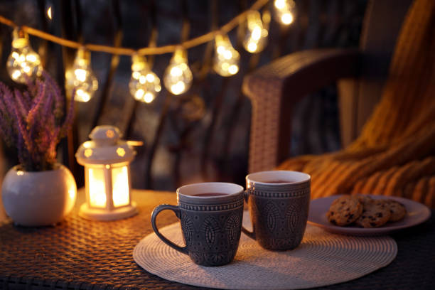 Cups with tasty cocoa on rattan table at balcony in evening