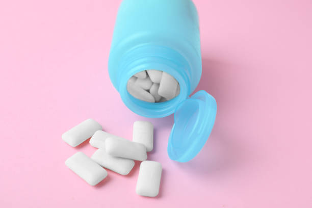 Jar with chewing gums on pink background, closeup