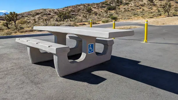 ADA Wheelchair accessible cement picnic table in a parking area of a desert recreation area