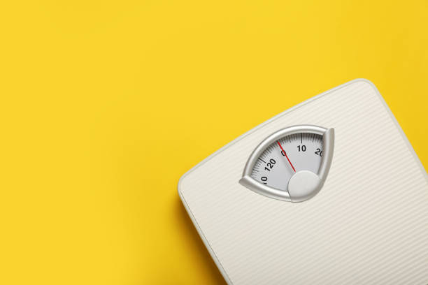 istock Weigh scales on yellow background, top view with space for text. Overweight concept 1812038618
