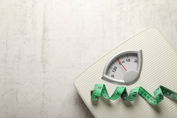 istock Weigh scales and measuring tape on white textured background, top view with space for text. Overweight concept 1812039149