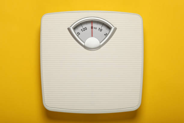 istock Weigh scales on yellow background, top view. Overweight concept 1812039178