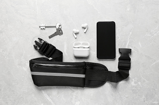 Flat lay composition with black waist bag on light grey table