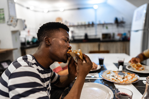 Young man eating pizza at home