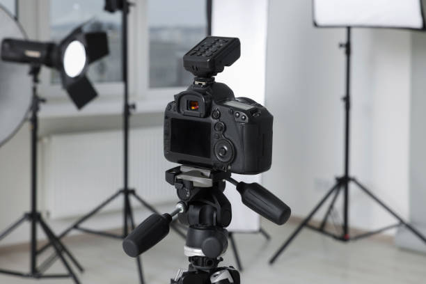 istock Camera on tripod and professional lighting equipment in modern photo studio 1812073386