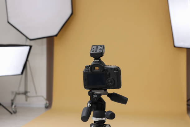 istock Camera on tripod and professional lighting equipment in modern photo studio 1812073392