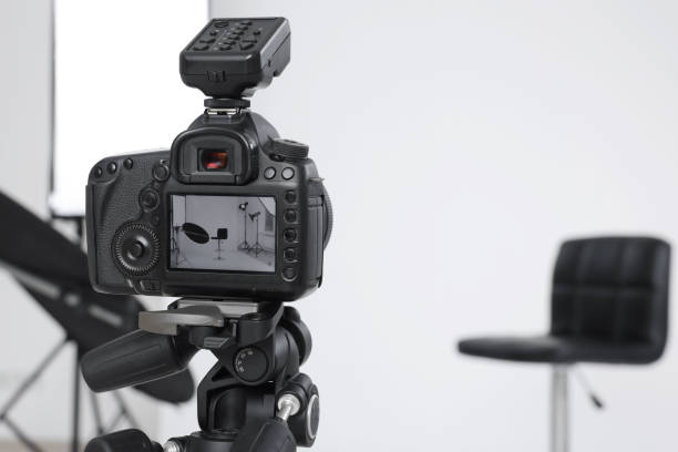 istock Tripod with camera, bar stool and professional lighting equipment in modern photo studio, focus on screen. Space for text 1812073668