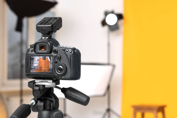 istock Tripod with camera, bar stool and professional lighting equipment in modern photo studio, focus on screen. Space for text 1812074456