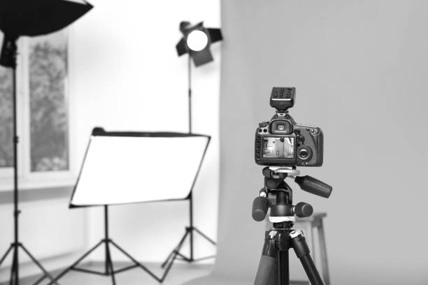 istock Camera on tripod, bar stool and professional lighting equipment in modern photo studio, space for text 1812074491