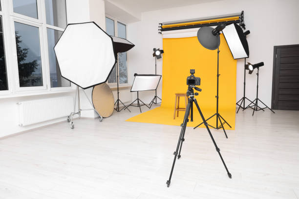 istock Camera on tripod, bar stool and professional lighting equipment in modern photo studio 1812075009