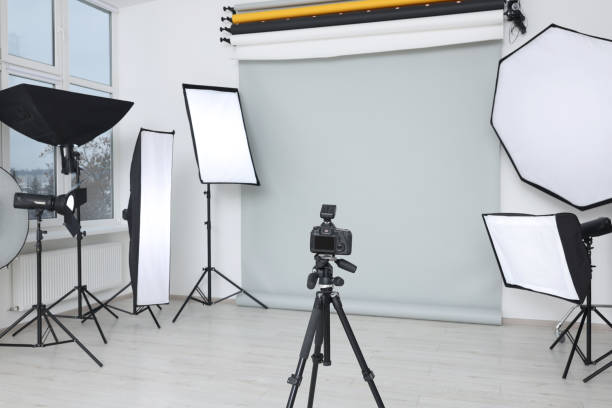 istock Camera on tripod and professional lighting equipment in modern photo studio 1812075611