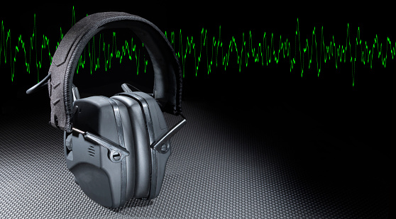 Electronic headphones to protect hearing with a green sine wave running behind