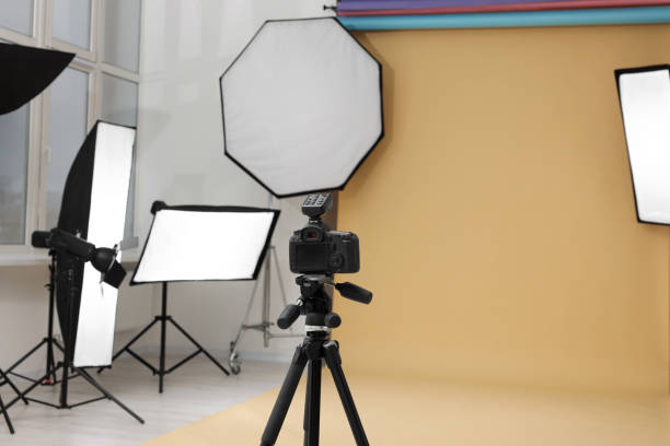 istock Camera on tripod and professional lighting equipment in modern photo studio 1812076170