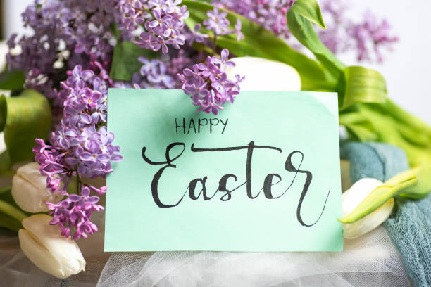 Blooming lilac branches and white tulips with the inscription Happy Easter
