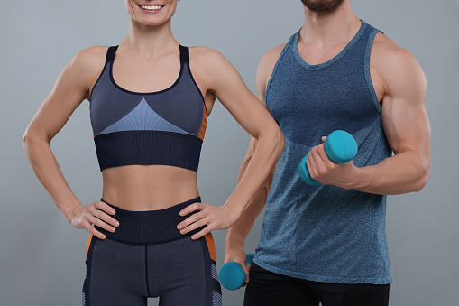 Athletic people with dumbbells on grey background, closeup