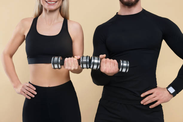 istock Athletic people exercising with dumbbells on light brown background, closeup 1812123334