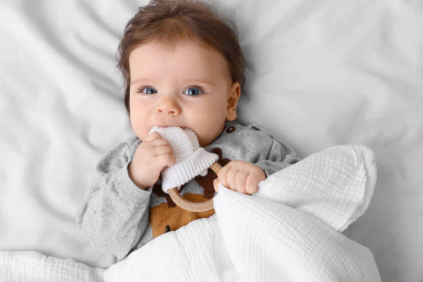 istock Cute little baby with toy on soft bed, top view 1812143533