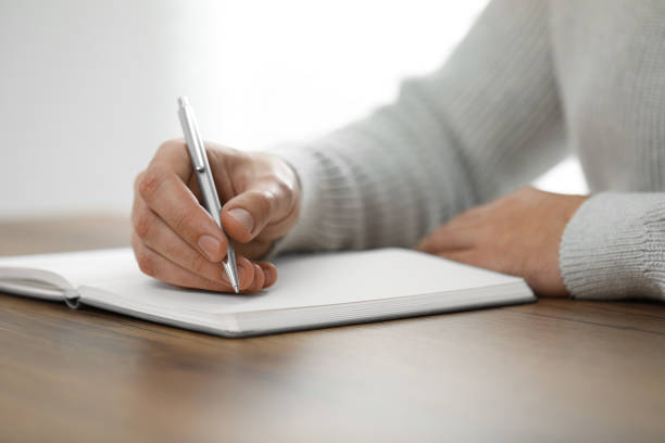 istock Man writing in notebook at wooden table, closeup 1812164578