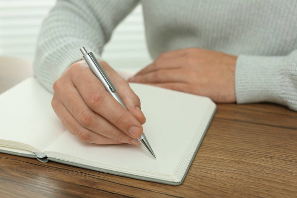 istock Man writing in notebook at wooden table, closeup 1812164583