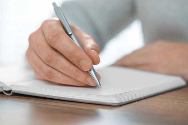 istock Man writing in notebook at wooden table, closeup 1812165099