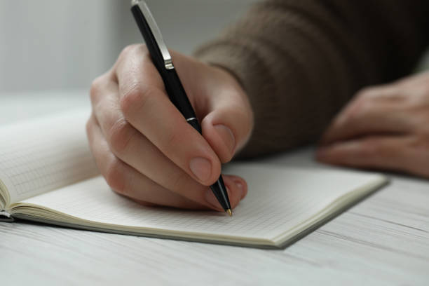 istock Man writing in notebook at white wooden table, closeup 1812165103