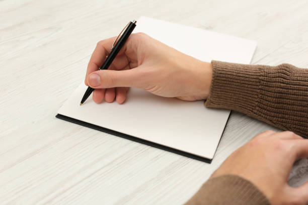 istock Man writing in notebook at white wooden table, closeup 1812165609