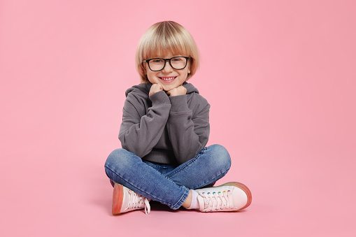 Carefree little kid girl sitting on sofa . Funny happy child playing and smiling. Family, vacation, childhood concept