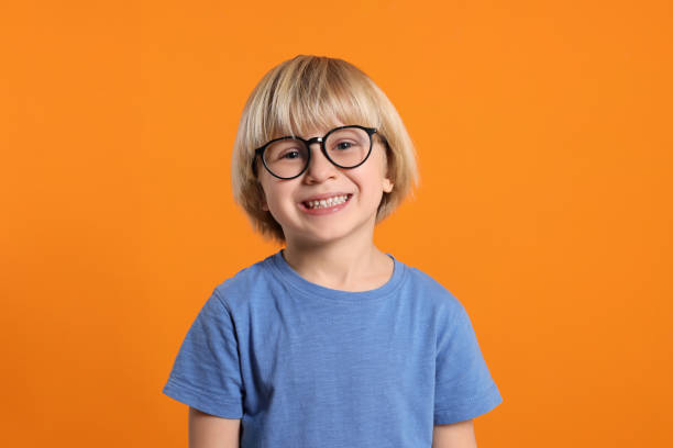 istock Cute little boy wearing glasses on orange background 1812166691