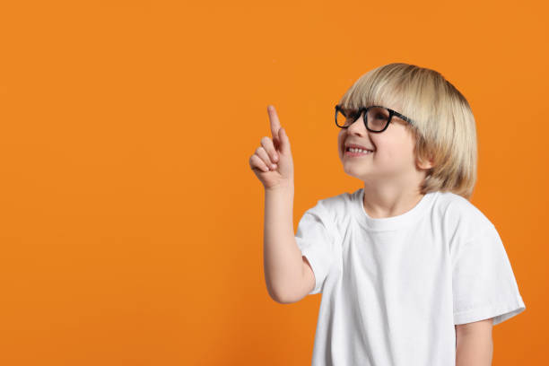 istock Cute little boy wearing glasses on orange background, space for text 1812168288