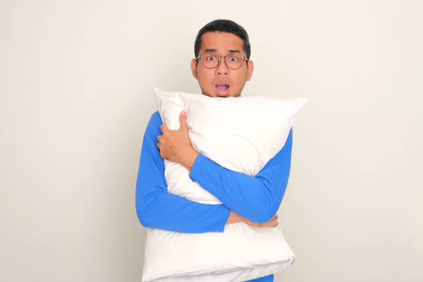 istock Adult Asian man showing shock expression while hugging a pillow 1812192530
