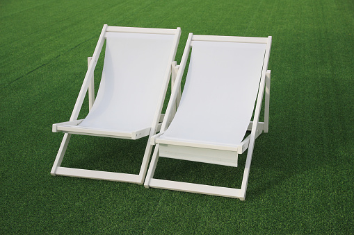 white beach deck canvas chair on the green grass