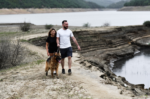 Stroll By The Lake For Smiling Couple And Their German Shepherd Dog