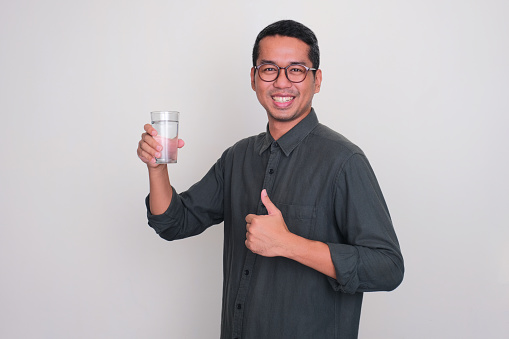 smiling face expression young asian man hold drinking glass. healthcare concept