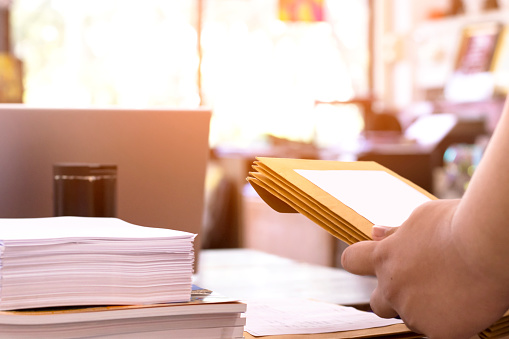 Office clerk or secretary is preparing documents and brown envelopes for those interested in bidding for the construction of a large building in an office.