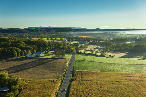 Drone shot of farms surrounded by rolling green fields in Lycoming County, Pennsylvania on a sunny day in Fall. The area is known for a large number of Mennonite and Amish communities.