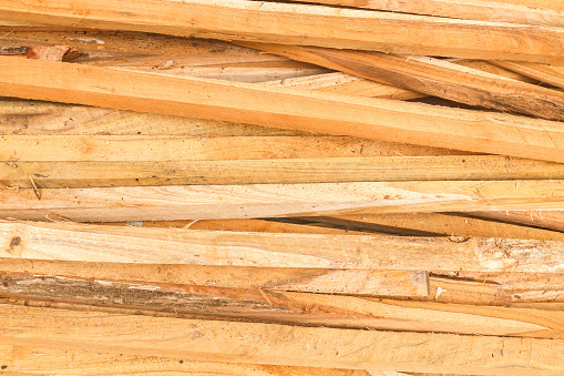 Long pieces of wood to make the roof of the house. Close-up of pieces of wood in a woodshed. Board background.