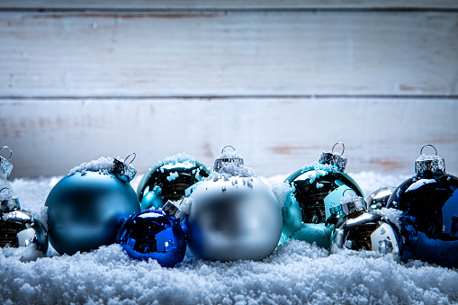 Blue and white christmas balls hanging on snow covered spruce branch closeup. Christmas tree decor concept