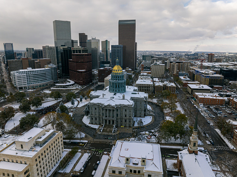 Aerial still image of the Colorado State Capitol Building in Denver, Colorado, taken by a drone on a cold day in the Fall after and early snowfall.