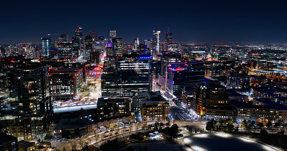 Drone shot of downtown Denver, Colorado on a cold night in Fall after an early fall of snow from over Commons Park, with Union Station visible among the office buildings.