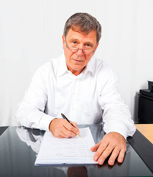 business-mann bei seinem schreibtisch - pen explaining single word symbol stock-fotos und bilder