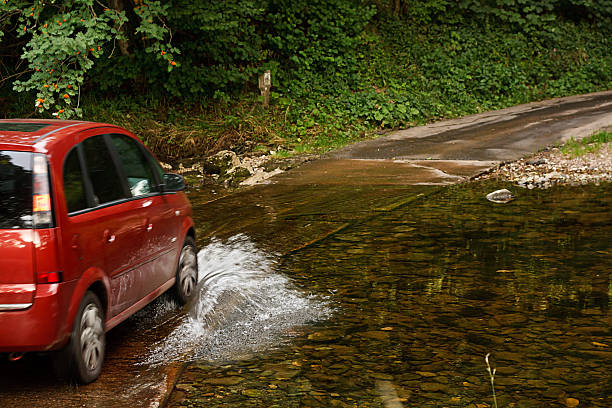 family car crossing a river at ford Family Car fording a river at ford an old fashioned way of crossing water without building a bridge ford crossing stock pictures, royalty-free photos & images